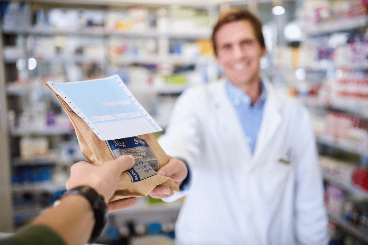 Apotheker überreicht einem Kunden seine Bestellung in der Apotheke